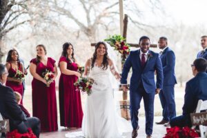 Hollow Hill Event Center Wedding and Event Venue, Weatherford, Texas. Bride and groom smiling exciting ceremony. Wedding party in back ground