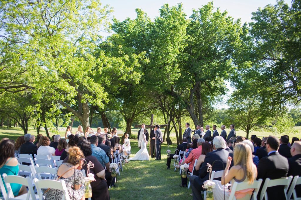 Hollow Hill Event Center Wedding and Event Venue, Weatherford, Texas. Outdoor wedding ceremony in clearing with trees around.