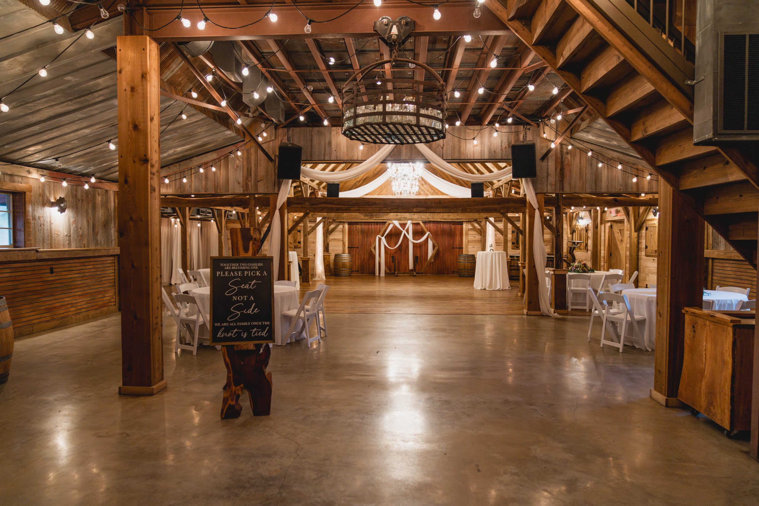 Hollow Hill Event Center Wedding and Event Venue, Weatherford, Texas. Large open room with round tables and chairs and stained concrete floors. Dark good walls and ceiling
