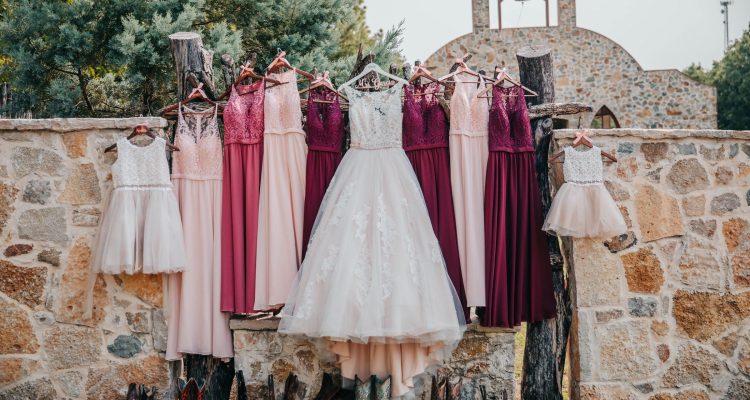 Hollow Hill Event Center Wedding and Event Venue, Weatherford, Texas. Brides and bridesmaids dresses and boots handing on stone wall in front of stone alamo style building.